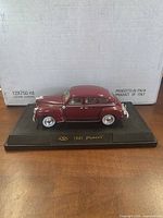 Left side view of burgundy 1941 Plymouth model on labeled base