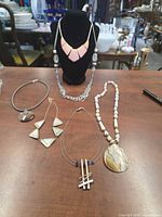 Group view of all six necklaces displayed on table and bust