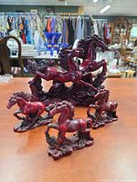 Front view showing four burgundy resin horse figurines on tabletop