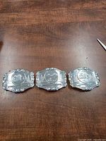 three identical chrome belt buckles front view