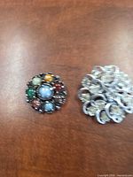 Both brooches side by side on surface