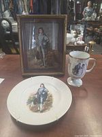 Plate, pedestal mug and framed print on tabletop