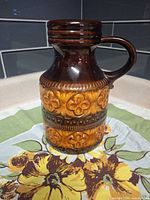 Full view of pitcher showing glaze colors, floral relief, handle