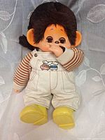 Front view of Monchichi doll showing overalls, shirt, boots and face