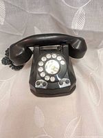 Front view of bakelite rotary telephone showing dial and line buttons