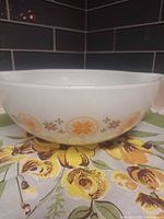 Side view showing orange/yellow medallion snowflake pattern on white milk glass bowl