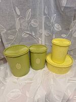 Four Tupperware containers with lids displayed together