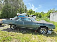 Driver side view of blue 1968 Buick Electra showing body, vinyl roof, missing left rear wheel cover