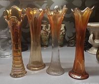 Front view of four iridescent carnival glass swung vases