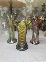 Front view of three carnival glass vases displaying color and patterns