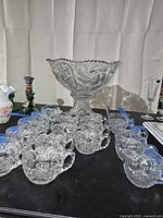Full view of pressed glass punch bowl on pedestal with surrounding cups