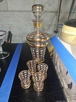 Decanter with stopper and four glasses showing gold lattice design