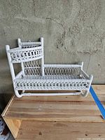 Front view of white wicker two-tier wall shelf on wood surface