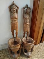 Front view of both carved figures and bowls