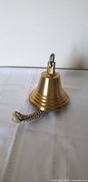Side view of polished brass bell with rope lanyard attached