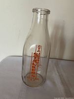 Full view of milk bottle front showing red lettering and overall shape