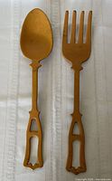 Front view of mustard-yellow cast iron spoon and fork showing design and color