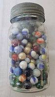 Full jar filled with multicoloured marbles, zinc lid visible