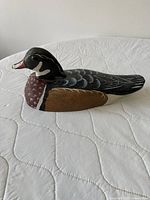 Left profile of carved and painted wood duck decoy on white surface