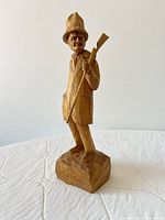 Front view of carved hunter figurine standing on faceted base