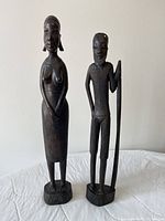 Front view of both ebony figurines on quilted surface