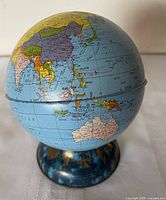 Front view of tin globe bank showing Asia, Australia and blue zodiac base