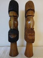 Front view of both wooden bearded busts showing facial carving and contrasting finishes