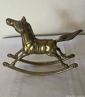 Left profile of brass rocking horse on rocker rails