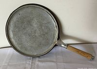 Top view of round aluminum griddle showing cooking surface and handle