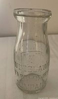 Front view showing embossed Woodlawn Farm Dairy Company lettering and shield logo