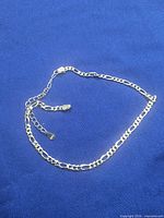 Entire anklet laid flat showing Figaro links and extender