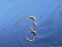 Both hoop earrings open showing inner construction and decorative outer band