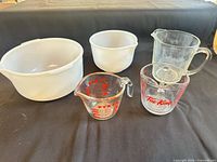 Group showing two white Glasbake bowls and three glass measuring cups