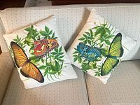 Two decorative pillows on sofa showing butterfly printed fronts