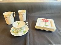 Front view of all dishes: two mugs, teacup, saucer, four plates