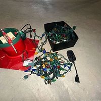 Tree stand, tangled string lights, black timer plug, flood bulb visible