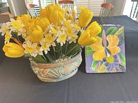 basket of artificial tulips and narcissus next to floral canvas