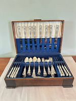 Open chest showing dinner knives in lid and assorted flatware in tray