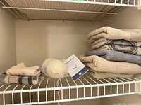 Folded hand towels, face cloths and mesh-covered dryer ball on wire shelf