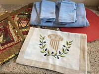 Overall view of blue tablecloth, napkins, patchwork runners, embroidered runner and red placemats