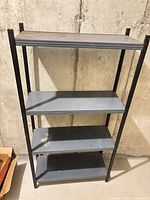 Full view of 4-tier metal storage rack against concrete wall