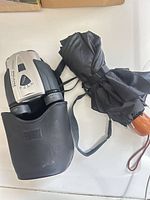 Binoculars in case next to folded umbrella