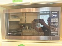 Front view of Panasonic microwave showing mirrored door, control panel, brand and time display