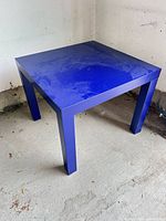 Full view of square blue side table showing top and legs