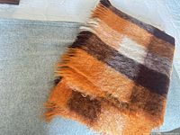 Folded mohair plaid throw showing colour blocks and fringe