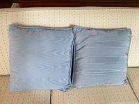 Both blue cushions side by side on sofa