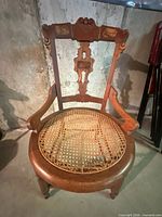 Full view of carved wooden chair with damaged cane seat