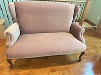 Full front view of dusty-rose upholstered loveseat with wingback sides and cabriole legs