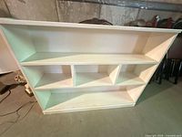 Front view of white painted wooden bookcase showing shelves and cubbies