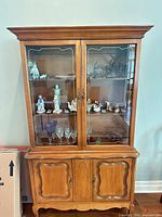 Front view of cabinet showing glass doors, lower wood doors, shelves
